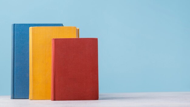 Vista frontal de tres libros de colores con espacio de copia