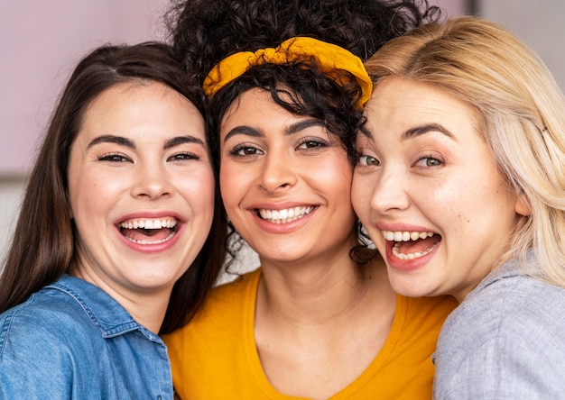 Vista frontal de tres mujeres felices posando juntos y sonriendo