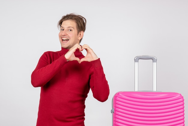 Vista frontal del turista masculino con bolsa rosa sobre pared blanca