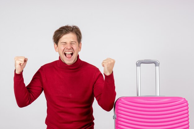 Vista frontal del turista masculino con bolsa rosa sobre pared blanca