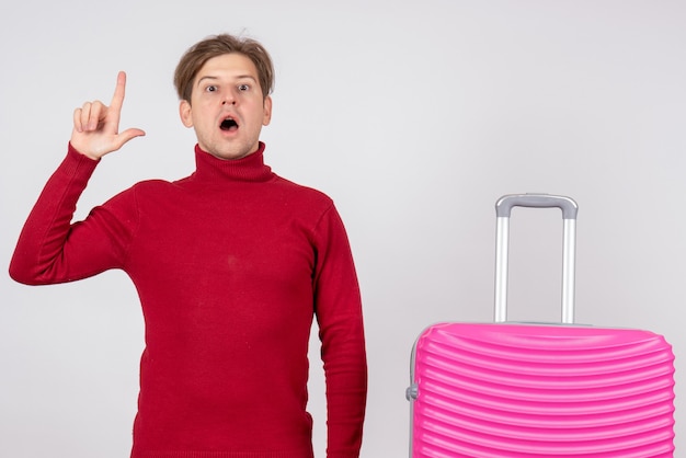 Vista frontal del turista masculino con bolsa rosa sobre pared blanca