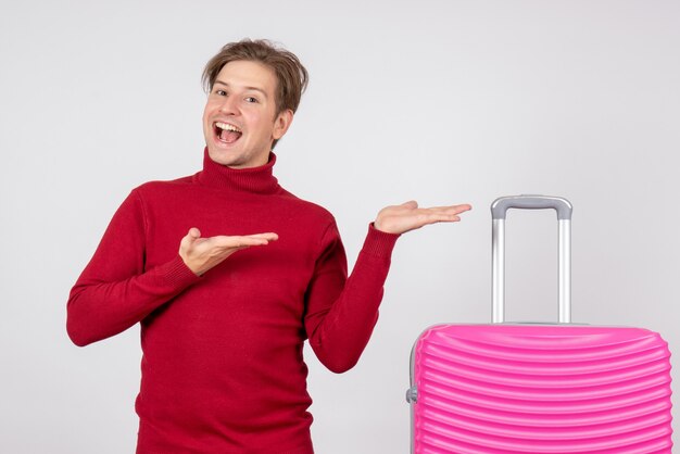 Vista frontal del turista masculino con bolsa rosa sobre pared blanca