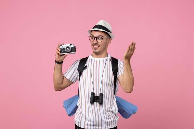 Vista frontal turista masculino sosteniendo la cámara en la pared rosa color turista emociones