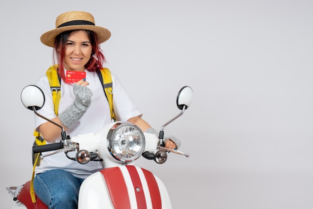 Vista frontal turista sentado en motocicleta sosteniendo la pared blanca de la tarjeta bancaria