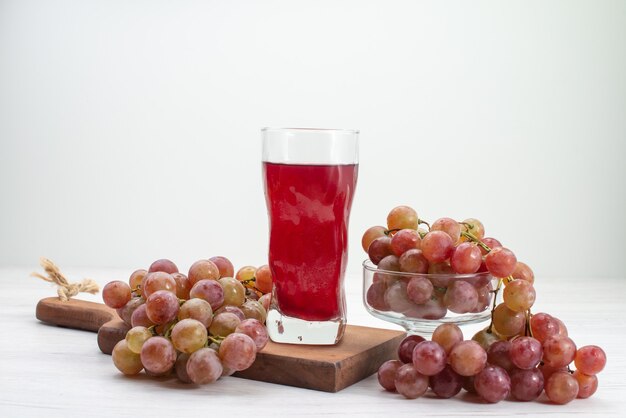 Vista frontal de uvas agrias frescas con jugo en el escritorio blanco bebida de jugo suave fresco de frutas