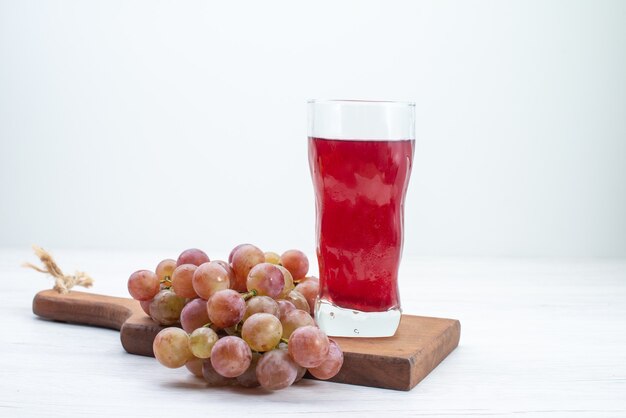 Vista frontal de uvas agrias frescas con jugo en el escritorio blanco frutas bebida de jugo suave fresco