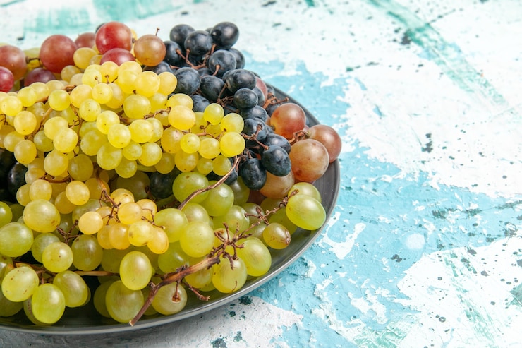 Foto gratuito vista frontal uvas de colores frescos frutas jugosas y suaves sobre una superficie azul claro