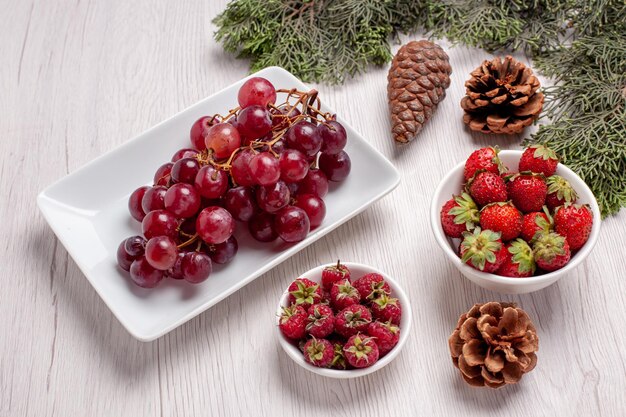Vista frontal de uvas frescas con frutas en el escritorio blanco color de jugo suave de frutas