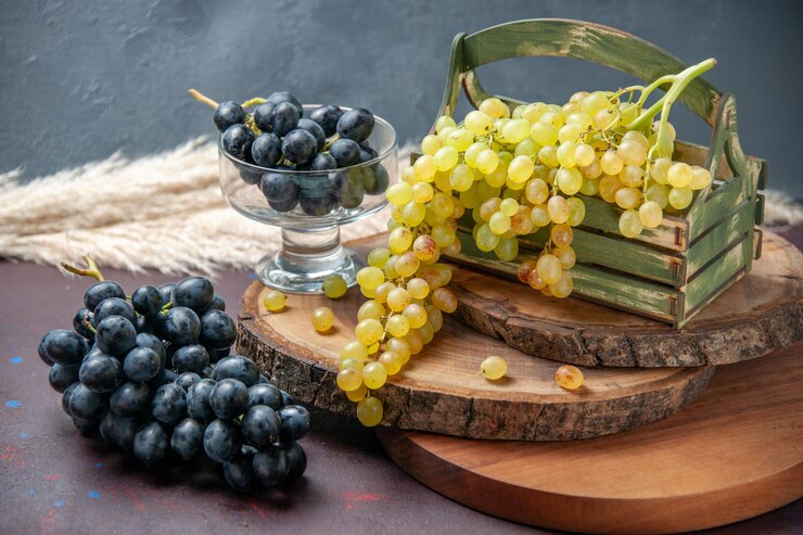 Foto gratuito vista frontal uvas frescas frutas verdes y negras sobre superficie oscura uva de vino fruta madura planta de árbol fresco