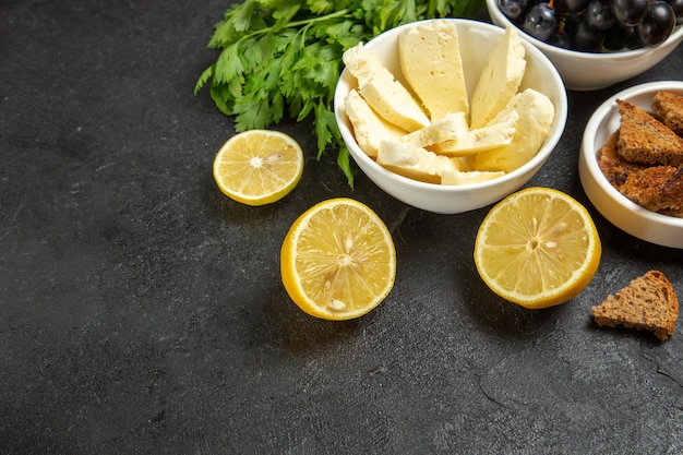 Foto gratuita vista frontal de uvas frescas con verduras de queso blanco y rodajas de limón sobre el fondo oscuro, comida, desayuno, plato, leche, fruta