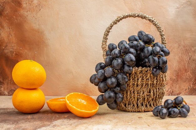 Vista frontal uvas negras frescas con naranja sobre fondo claro foto jugo color fruta suave