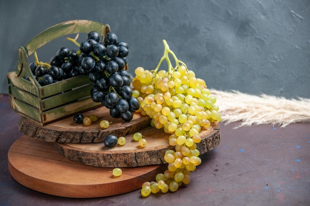 Vista frontal de uvas suaves frescas frutas oscuras y verdes en la superficie oscura uva de vino fruta madura planta de árbol fresco