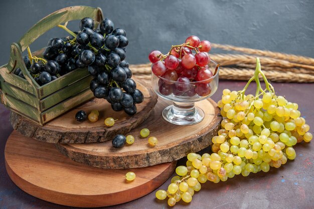 Vista frontal de uvas suaves frescas frutas oscuras y verdes en la superficie oscura vino uva fresca fruta planta de árbol maduro