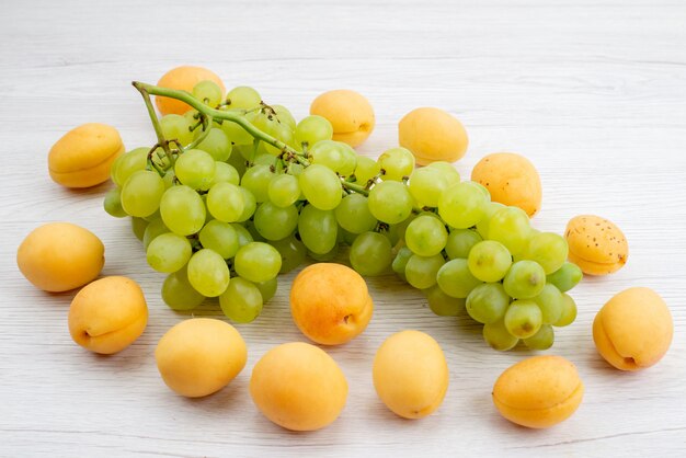 Una vista frontal de uvas verdes frescas con albaricoques en el escritorio blanco fruta color verde verano