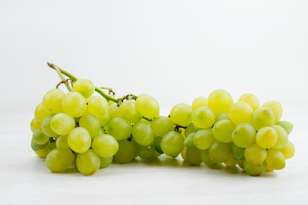 Una vista frontal de las uvas verdes frescas jugosas y agrias en el escritorio blanco de verano vitamina color fruta