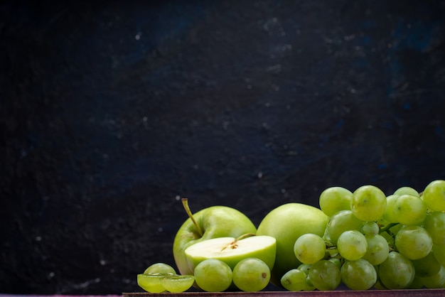 Vista frontal de uvas verdes con manzanas verdes en la oscuridad