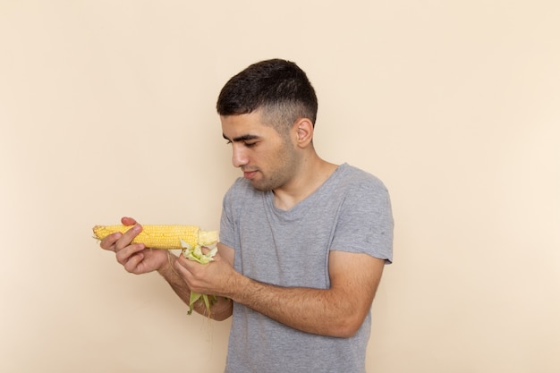 Vista frontal del varón joven en camiseta gris con maíz crudo en beige