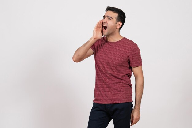 Vista frontal del varón joven en camiseta posando gritando sobre fondo blanco.