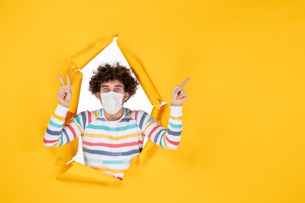 Vista frontal del varón joven con máscara estéril en color amarillo rasgado covid- salud pandemia humana virus