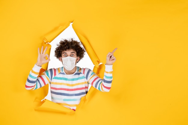 Vista frontal del varón joven con máscara estéril en color amarillo rasgado covid- salud pandemia humana virus