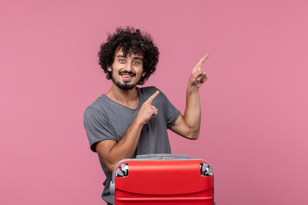 Foto gratuita vista frontal del varón joven preparándose para las vacaciones sonriendo en el espacio rosa