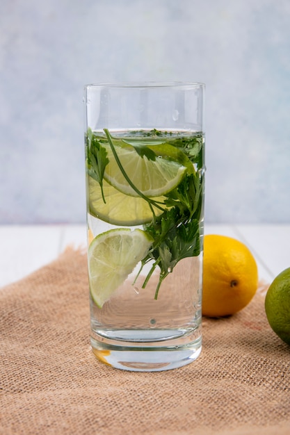 Foto gratuita vista frontal del vaso de agua con verduras y limón en una servilleta beige