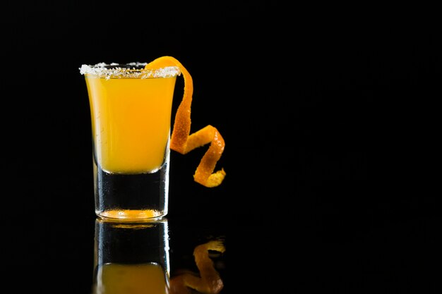 Vista frontal del vaso de chupito con cóctel de naranja