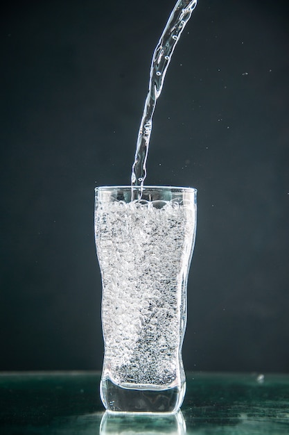 Vista frontal de un vaso de refresco que se vierte sobre la bebida oscura foto champán agua de navidad