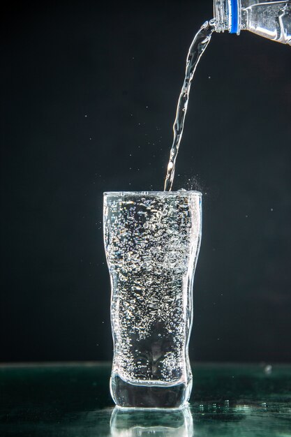 Vista frontal de un vaso de refresco que se vierte sobre la bebida oscura foto champán agua de navidad