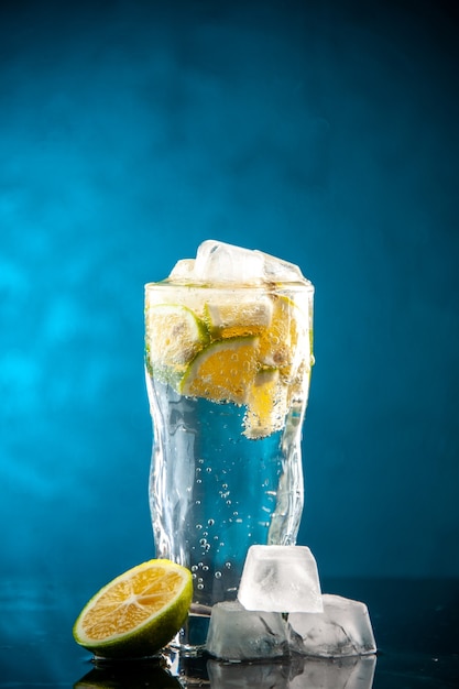 Vista frontal vaso de refresco con rodajas de limón y cubitos de hielo en azul foto champagne agua cóctel bebida limonada