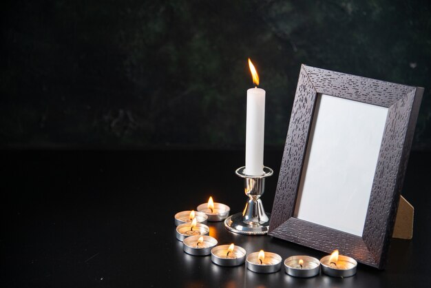 Vista frontal de velas encendidas como memoria de caídos sobre superficie negra