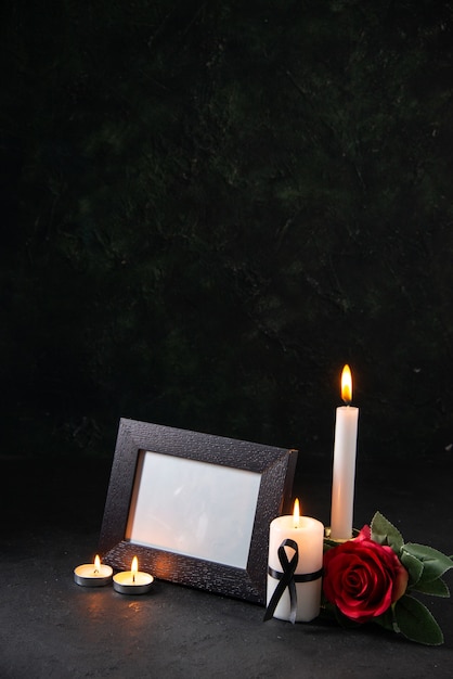 Vista frontal de velas encendidas con marco de imagen sobre una superficie oscura