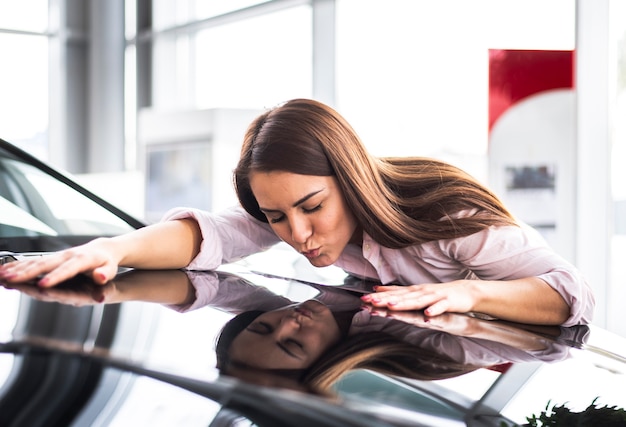 Foto gratuita vista frontal del vendedor de automóviles mujer besando coche