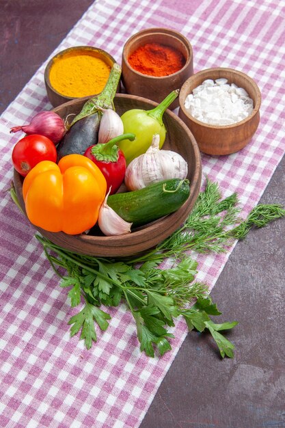 Vista frontal de verduras frescas con condimentos sobre fondo oscuro ensalada madura comida saludable almuerzo