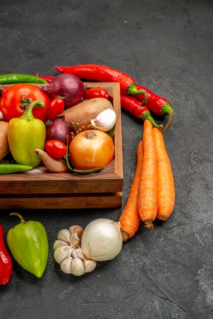 Vista frontal de verduras frescas con pimienta y ajo en el color de ensalada madura de mesa oscura