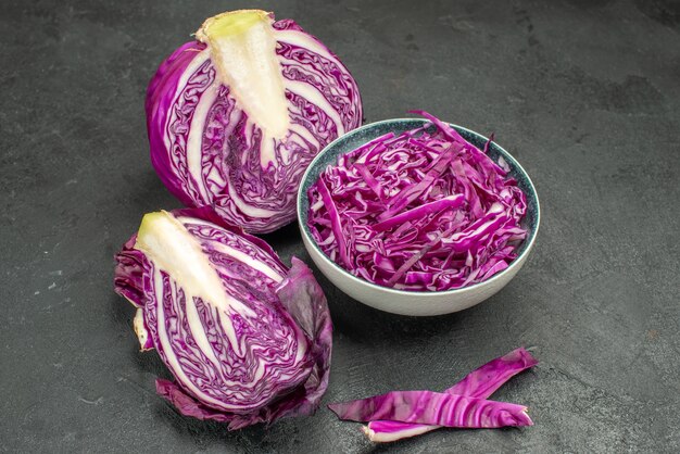 Vista frontal de verduras frescas de repollo rojo en rodajas en la mesa oscura