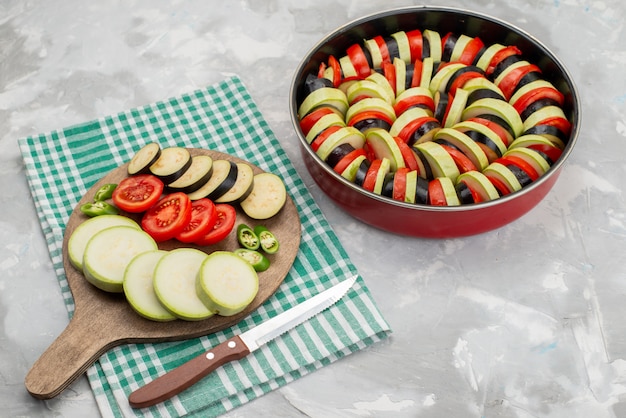 Vista frontal de verduras en rodajas como tomates y berenjenas frescas y cocidas en blanco