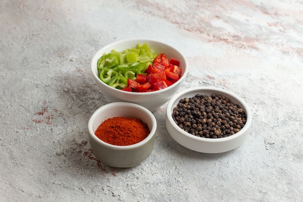 Foto gratuita vista frontal de verduras en rodajas con pimienta o sobre superficie blanca