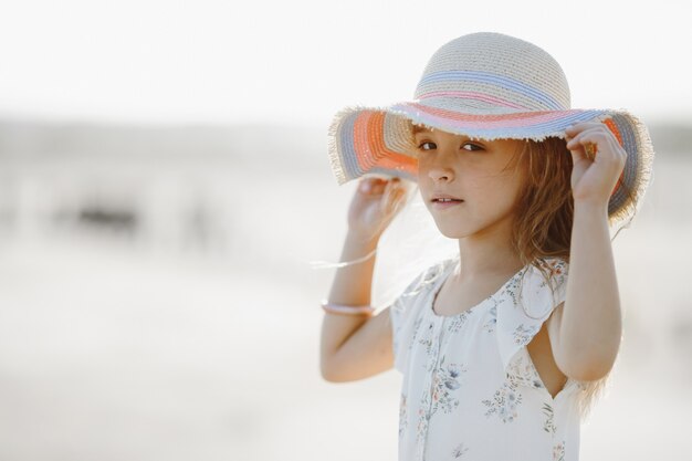 La vista frontal en vestido de verano se ve recta y sostiene los bordes del sombrero