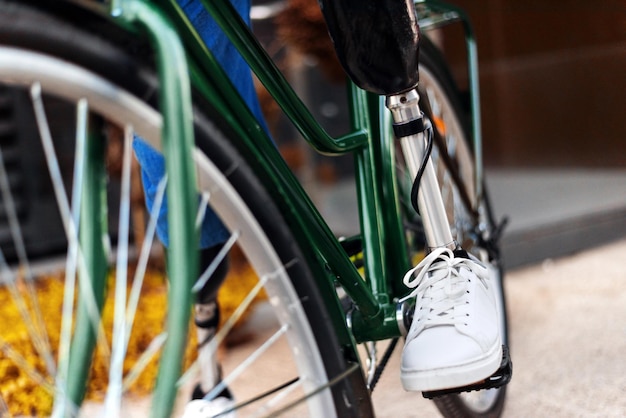 Foto gratuita vista de un hombre con piernas ortopédicas y zapatillas blancas sentado en su bicicleta