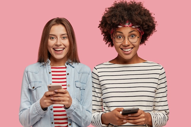 Foto gratuita vista horizontal de adolescentes adictos interraciales felices tienen celulares modernos en las manos