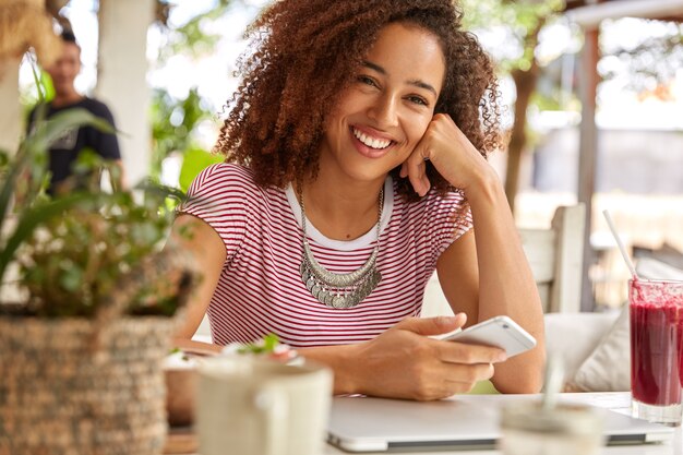 Vista horizontal de la atractiva adolescente tiene una sonrisa positiva en la cara