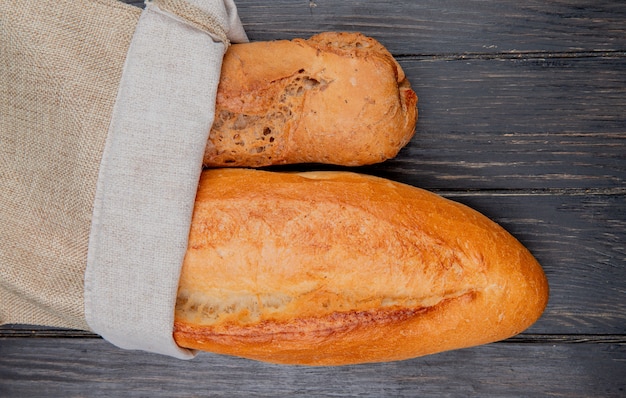 Vista horizontal de baguettes como negro y vietnamita en saco sobre superficie de madera