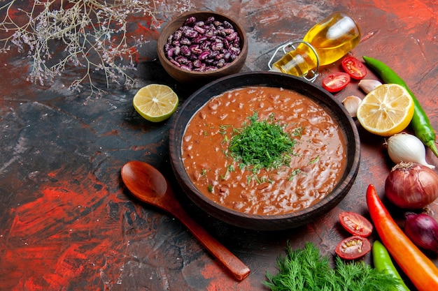 Vista horizontal de la botella de aceite de sopa de tomate frijoles limón y un montón de verde en la tabla de colores mezclados