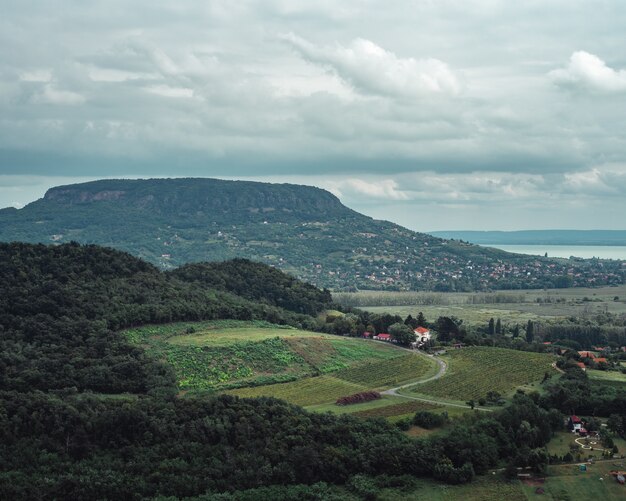 La vista horizontal de los campos y colinas en la orilla de un lago en un día nublado