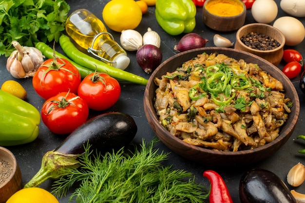 Vista horizontal de la deliciosa comida de berenjena, verduras frescas, especias, botella de aceite caída, paquete verde sobre fondo de color oscuro