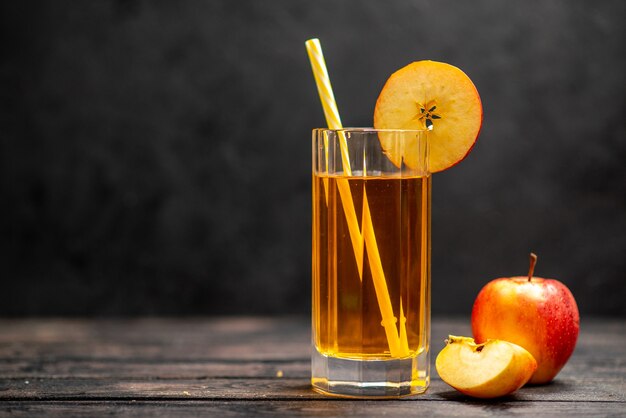 Vista horizontal de delicioso jugo natural fresco en dos vasos con limones de manzana roja sobre fondo negro