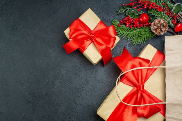 Vista horizontal del estado de ánimo de Navidad con hermosos regalos y ramas de abeto cono de coníferas sobre fondo oscuro