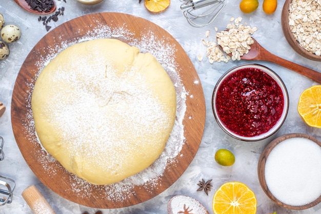 Foto gratuita vista horizontal de la masa cruda en un rallador redondo de madera y un conjunto de alimentos sobre fondo de hielo