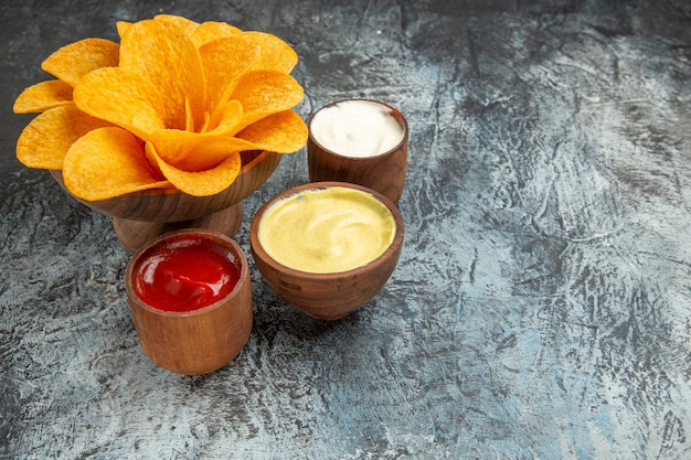 Vista horizontal de papas fritas crujientes decoradas como sal en forma de flor y mayonesa y salsa de tomate en mesa gris